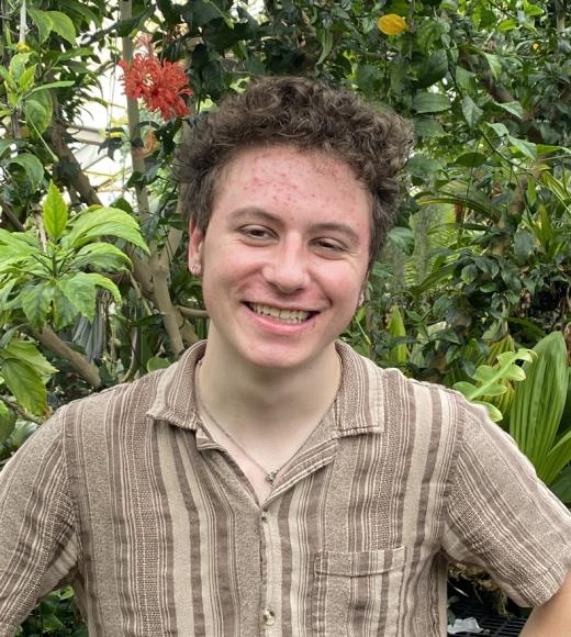 A student surrounded by plants smiling